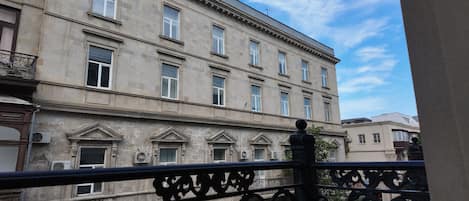 A multi-story building with a classical architectural style, featuring a balcony with ornate metal railings.