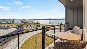 A balcony with a view of a lake and parking area. - Lakeview Condo | Seasonal Hot Tub | Pool | Restaurant (Canandaigua)