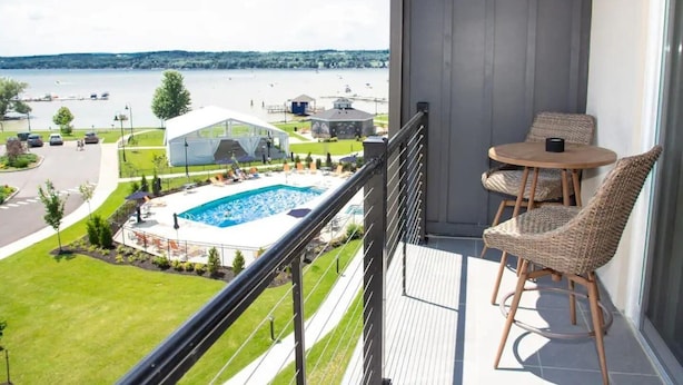 A balcony with a view of a swimming pool and a white tent. - Lakeview Condo | Seasonal Hot Tub | Pool | Restaurant (Canandaigua)