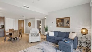 A modern living room with a grey sofa, a dining table with chairs, and a kitchen area in the background. - Canandaigua Condo w/ Restaurant and Pool/Hot Tub (Canandaigua)