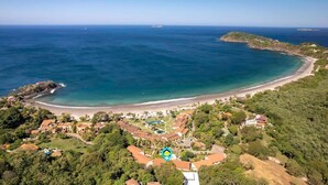 Vue aérienne d’une zone côtière comprenant une plage, des immeubles résidentiels et une vaste étendue d’eau.