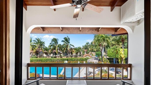 Un balcon avec vue sur une piscine et un paysage tropical.