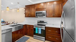 Une cuisine moderne avec des meubles en bois, des appareils électroménagers en acier inoxydable et des luminaires suspendus.