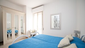 A bedroom with a large bed, a chair, a wardrobe, and a window. - Villa Torchio (Manerba del Garda)