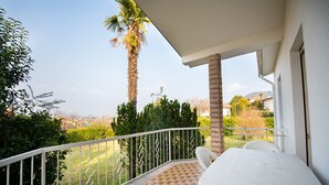 A balcony with a white table and chairs, a view of a palm tree, and a tiled floor. - Villa Torchio (Manerba del Garda)