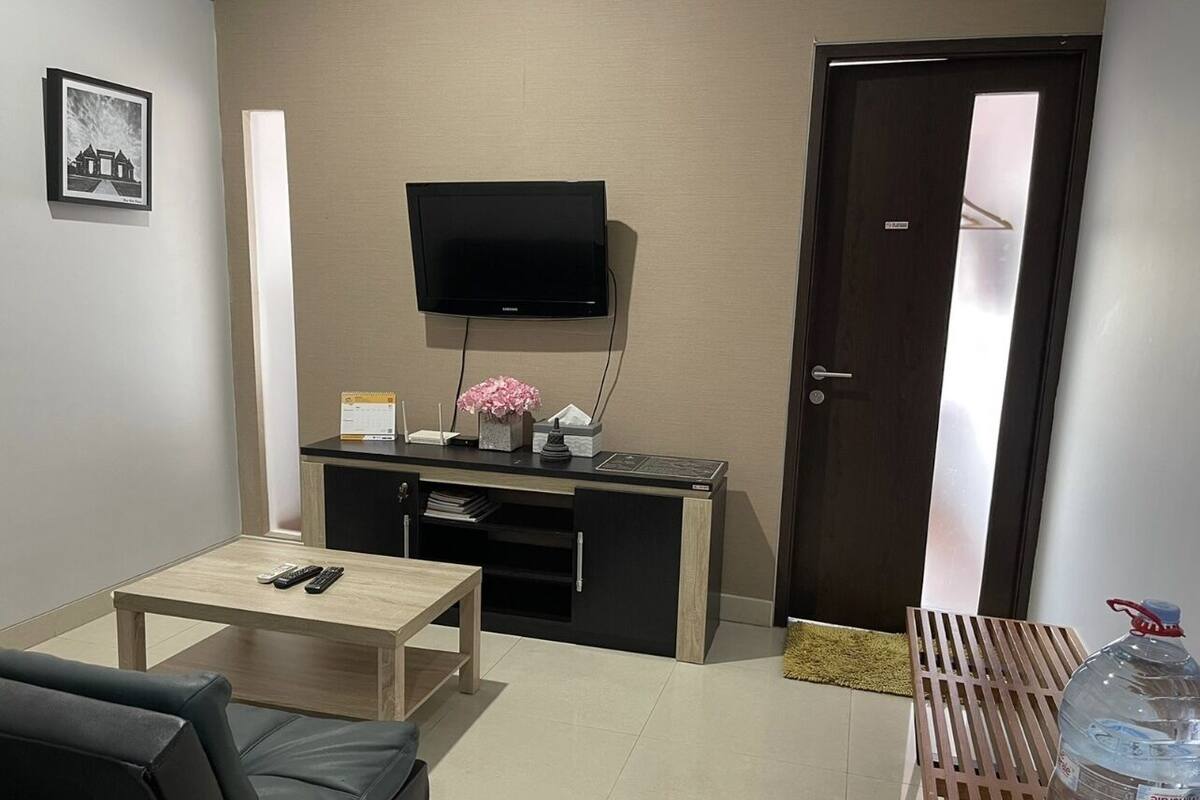 A living room with a TV, a coffee table, a sofa, a cabinet, and a water bottle.