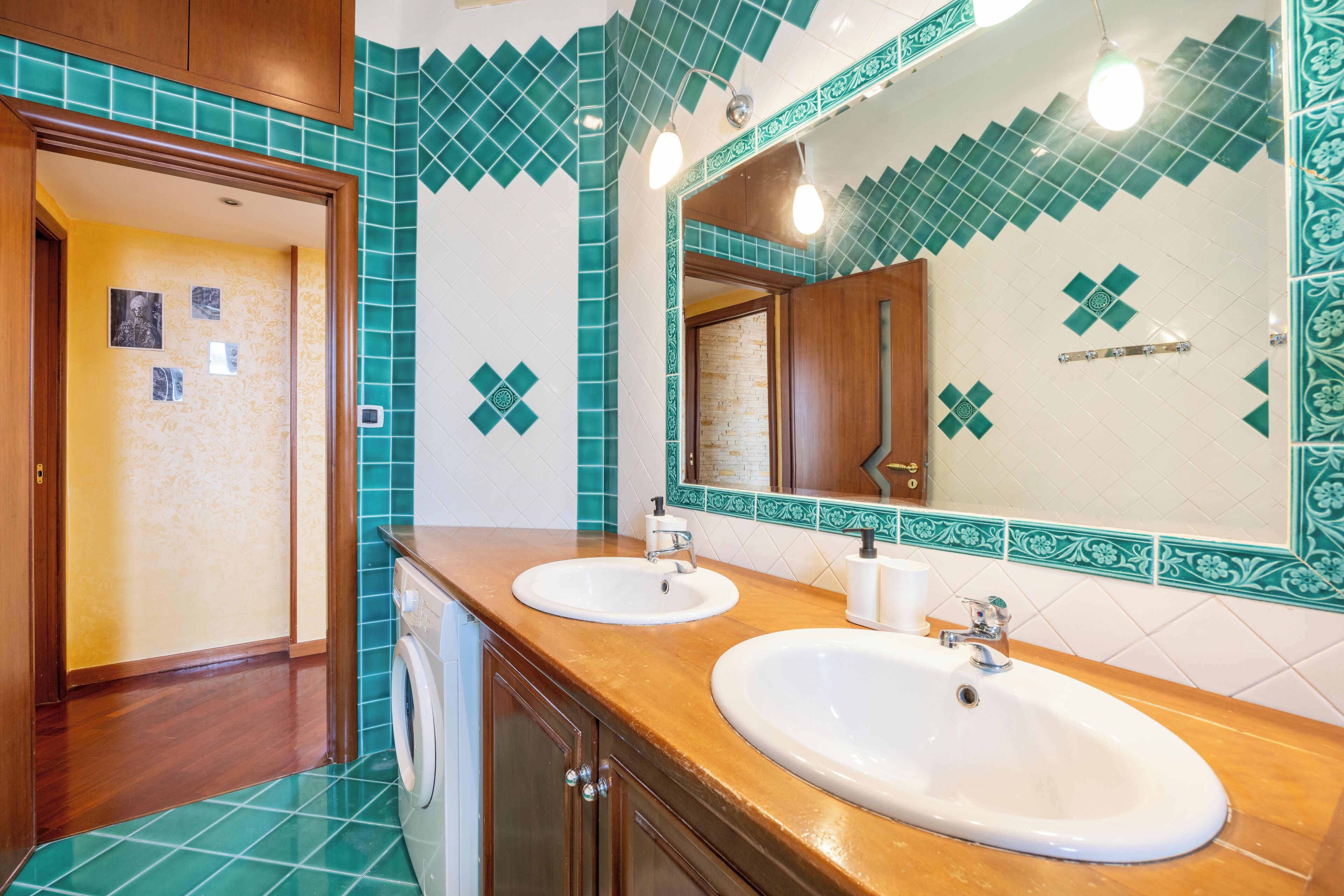 Ein Badezimmer mit zwei Waschbecken, einem Spiegel und einer Waschmaschine.