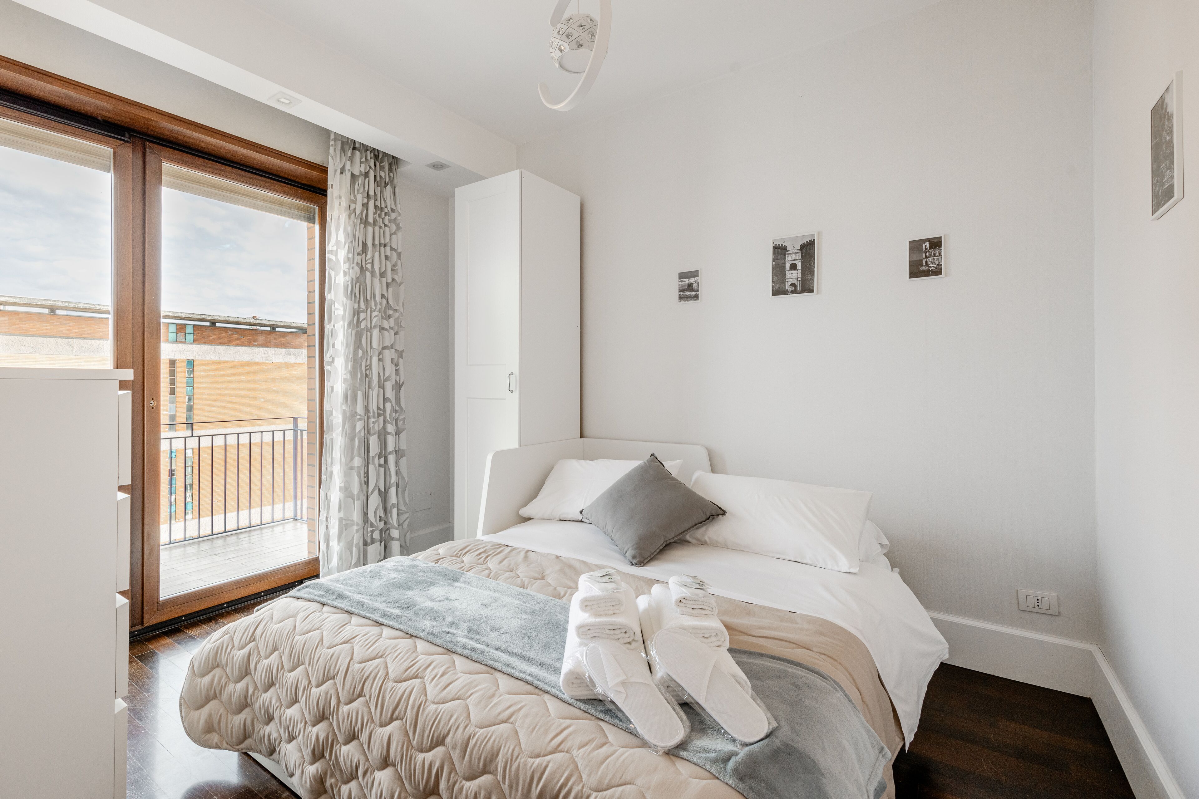 A bedroom with a bed, a window, and a door to an outdoor balcony.