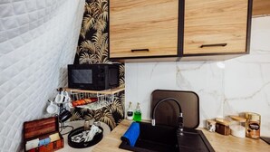 A compact kitchen with a microwave, sink, and wooden cabinets. - Karkonoski Glamping 2 sleeps 5 (Lomnica)