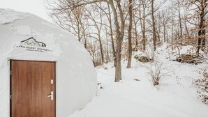 A snow-covered igloo with a wooden door and a logo above it. - Karkonoski Glamping 2 sleeps 5 (Lomnica)