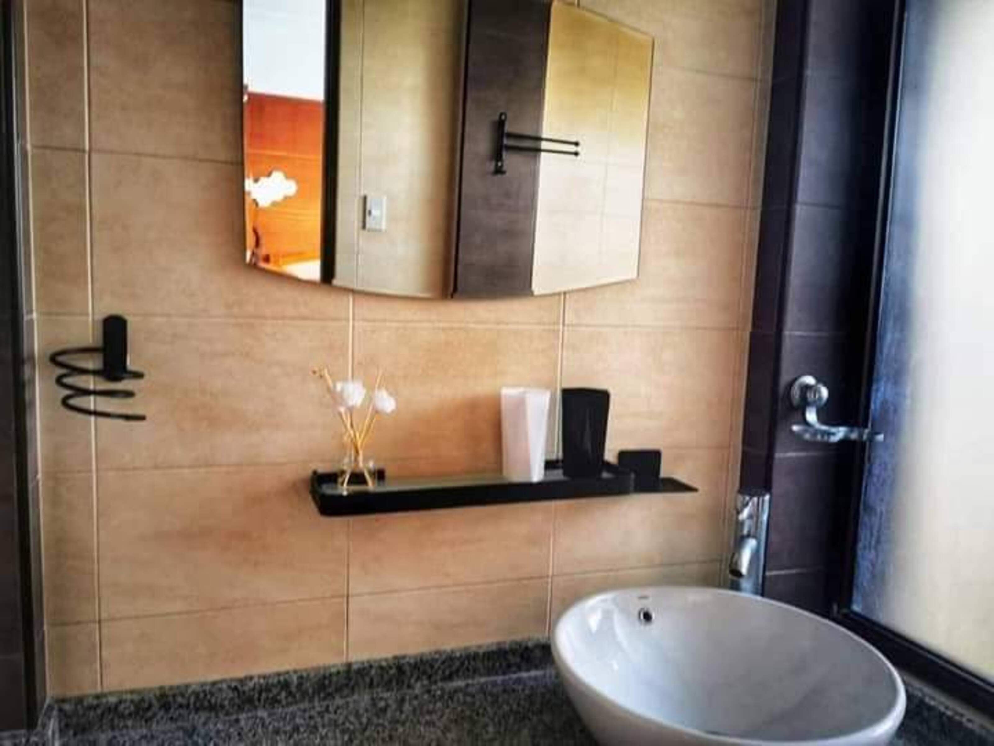 A modern bathroom with a large sink, a mirror, and a towel rack.