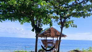 A thatched-roof hut with a hammock under a tree by the sea. - Seaheart Guesthouse (Dauis)