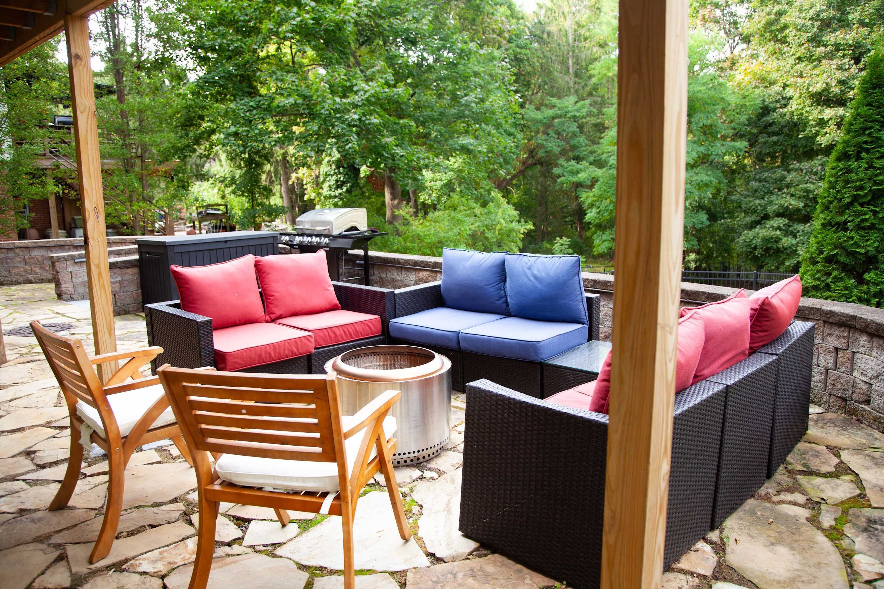 An outdoor patio with wicker furniture, stone flooring, and a view of a wooded area.