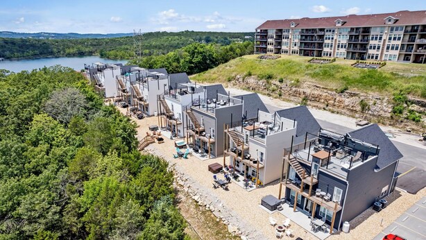 Un hôtel moderne à plusieurs étages, doté d’espaces extérieurs aménagés et offrant une vue sur un lac.