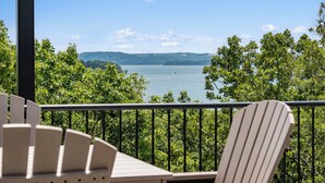 Un balcon avec vue sur un lac et des collines lointaines.