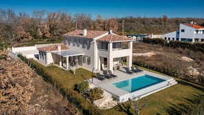 Une villa moderne dotée d’une piscine, d’un espace extérieur aménagé et d’une façade en pierre.