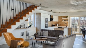 A modern living space with a staircase, a sofa, a coffee table, and a kitchen area. - Villa LeGro by Villas Guide (Rapavel)