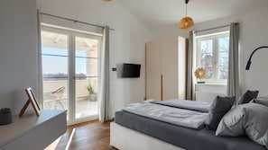 Une chambre moderne avec un lit, une télévision et un balcon.