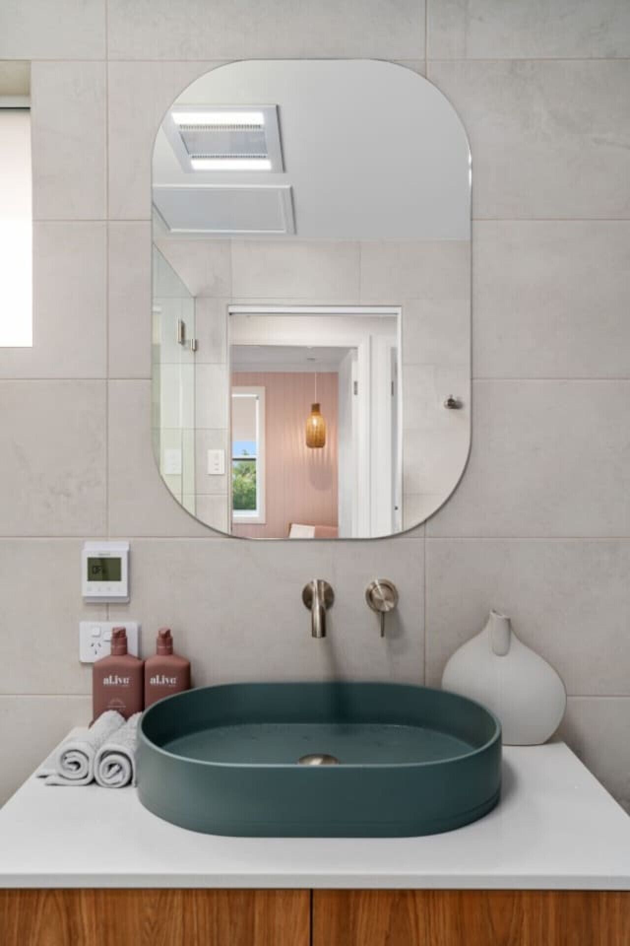 A bathroom with a round sink, a mirror, and a towel rack.