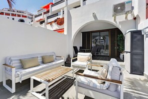 A modern outdoor seating area with a sofa, chairs, and a wooden table.