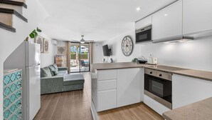 A modern kitchen with white cabinets, a built-in oven, and a large clock. - Parque Santiago II Exceptional Duplex with terrace (Costa Adeje)