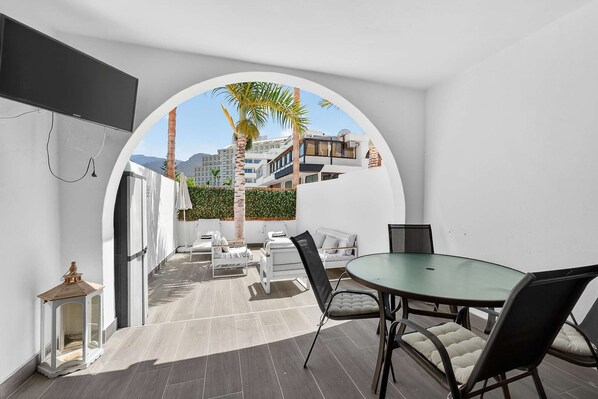A modern room with a glass table, chairs, and a view of a cityscape through an archway.