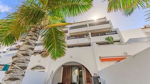 A multi-story building with balconies, a palm tree, and a clear sky. - Parque Santiago II Exceptional Duplex with terrace (Costa Adeje)