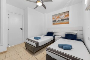 A bedroom with two beds, a ceiling fan, a world map, and a white door.