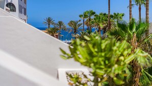 A white building with a clear view of the ocean and palm trees. - Parque Santiago II Exceptional Duplex with terrace (Costa Adeje)