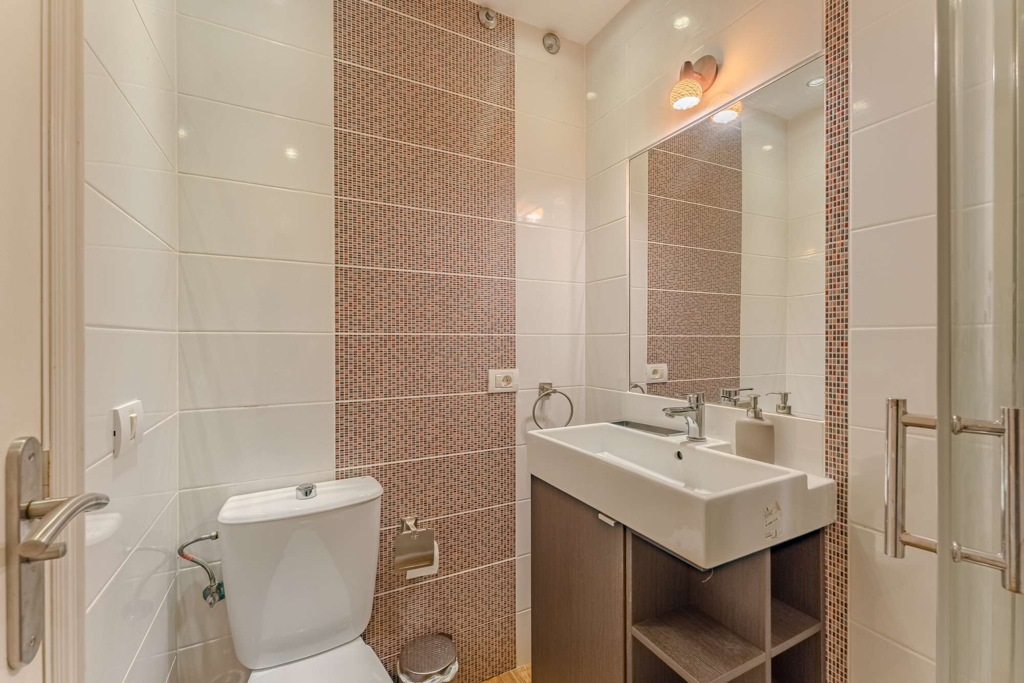 Et moderne badeværelse med toilet, vask og spejl.
