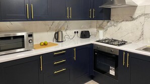 Une cuisine moderne avec des meubles de couleur bleu foncé, un four à micro-ondes en acier inoxydable, une cuisinière à gaz et un four encastré.