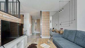 Ein modernes Wohnzimmer mit Flachbildfernseher, einer Couch, einem Couchtisch und einer Treppe.