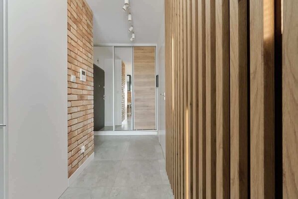A hallway with a brick wall, a sliding glass door, and a wooden panel wall.