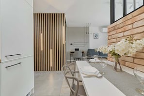 Una cocina moderna con comedor, pared de ladrillo decorativa y vista al salón.