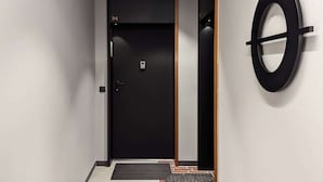 A modern hallway with a black door labeled "94", a circular wall decoration, and a small step leading to the door.
