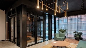 A modern office space with a glass partition, a round table, and green seating.