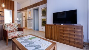 Una sala de estar moderna con un sofá, un mueble, un televisor y arte abstracto en la pared.