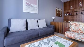 A modern living room with a grey sofa, a floral armchair, and a coffee table with abstract art.