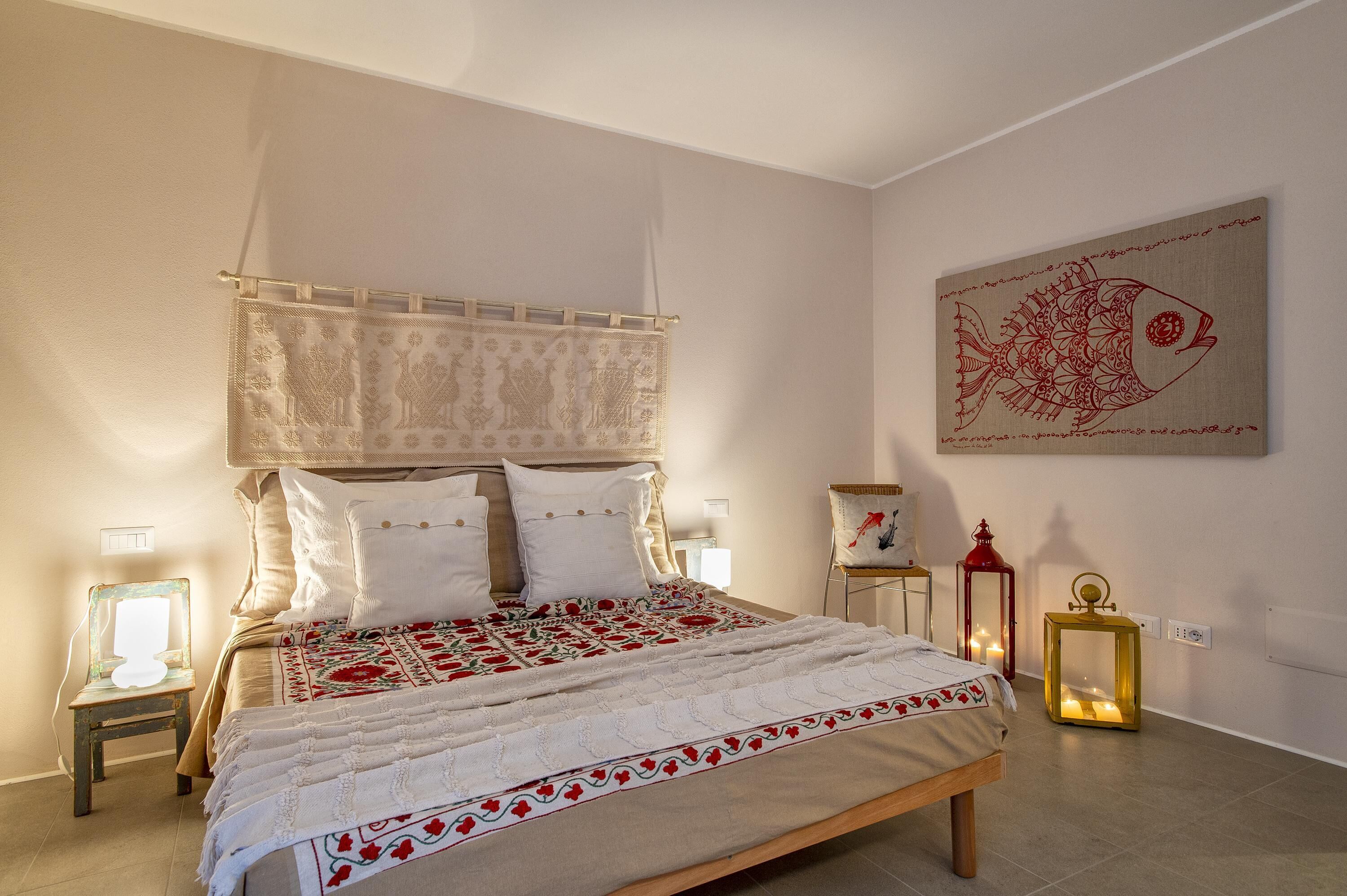 A bedroom with a bed, bedside tables, and wall art.