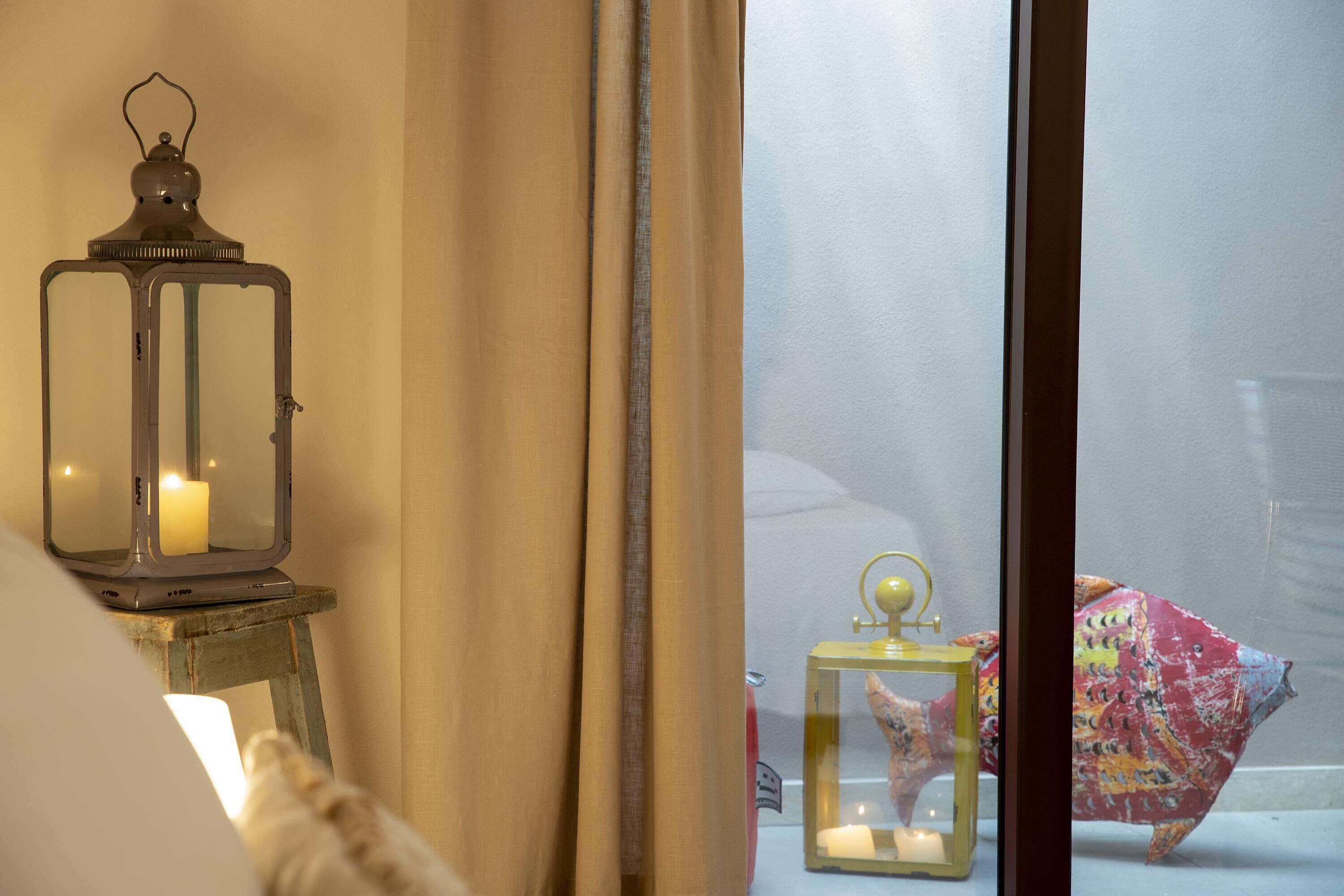 A room with a window, a candle in a lantern, and a fish decoration.