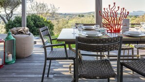 An outdoor dining area with a table set for two, wicker chairs, a green lantern, and a candle. - Sardinia Re - Villa Posta Del Sol (Alghero)