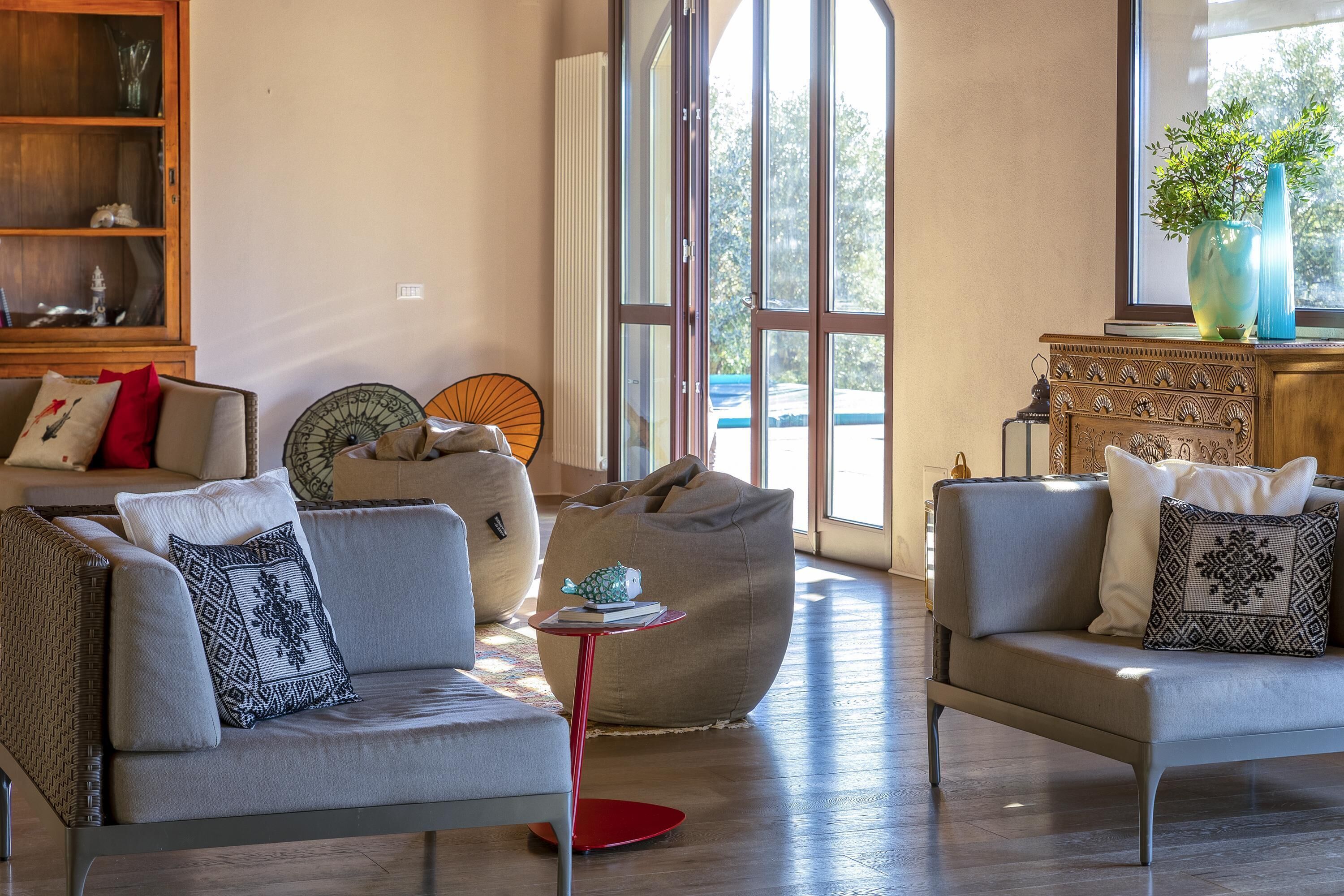Een woonkamer met twee banken, een bijzettafeltje, een loungestoel, een boekenkast en een raam met uitzicht.