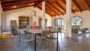A spacious dining area with a high wooden ceiling, a long table, and several chairs. - Sardinia Re - Villa Posta Del Sol (Alghero)