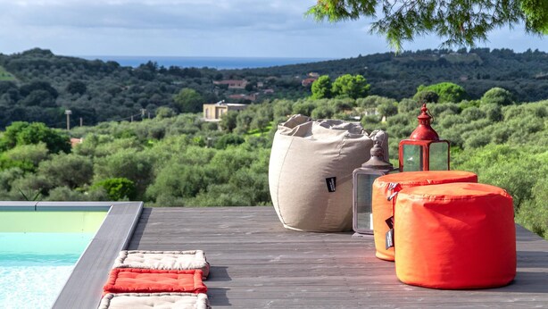 A poolside area with a view of a lush landscape and distant buildings. - Sardinia Re - Villa Posta Del Sol (Alghero)