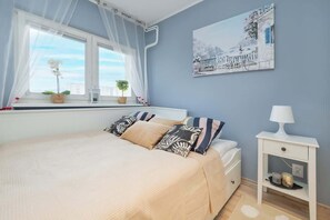 A cozy bedroom with soft blue walls, a neatly made bed with decorative pillows, and a white bedside table with a lamp for a warm ambiance.

 - Cozy Studio with Balcony | Quiet Neighborhood and Elevator (Lódz)