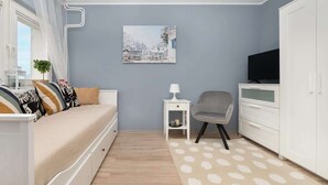 Un soggiorno moderno con un divano, un tavolino, una poltrona, una televisione e un'armadio.