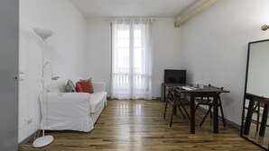 A small, bright room with a white sofa, a wooden dining table, and a TV. - Italianway Comfort - Fabbri 12 D (Milan)