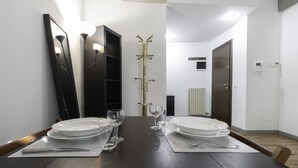 A dining area with a dark wooden table set for four, including plates, glasses, and cutlery. - Italianway Comfort - Fabbri 12 D (Milan)
