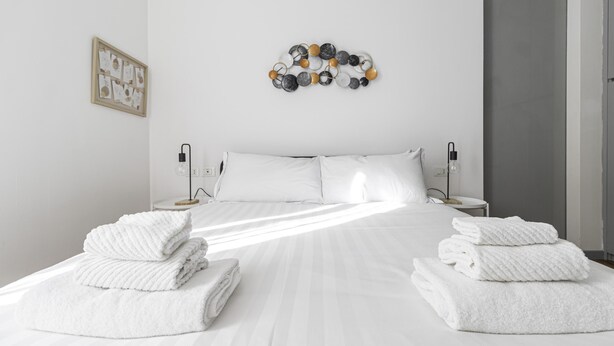 A neatly made bed with white linens, two bedside tables with lamps, and a wall decoration above the bed. - Italianway Comfort - Fabbri 12 D (Milan)