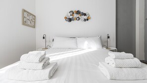 A neatly made bed with white linens, two bedside tables with lamps, and a wall decoration above the bed. - Italianway Comfort - Fabbri 12 D (Milan)